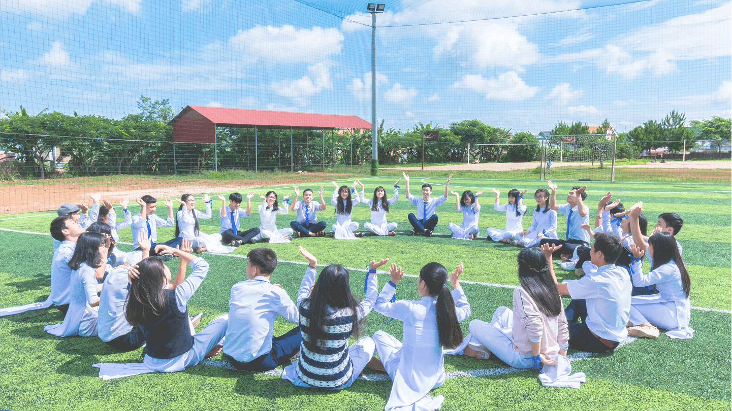 Students sitting in a circle on a sports field